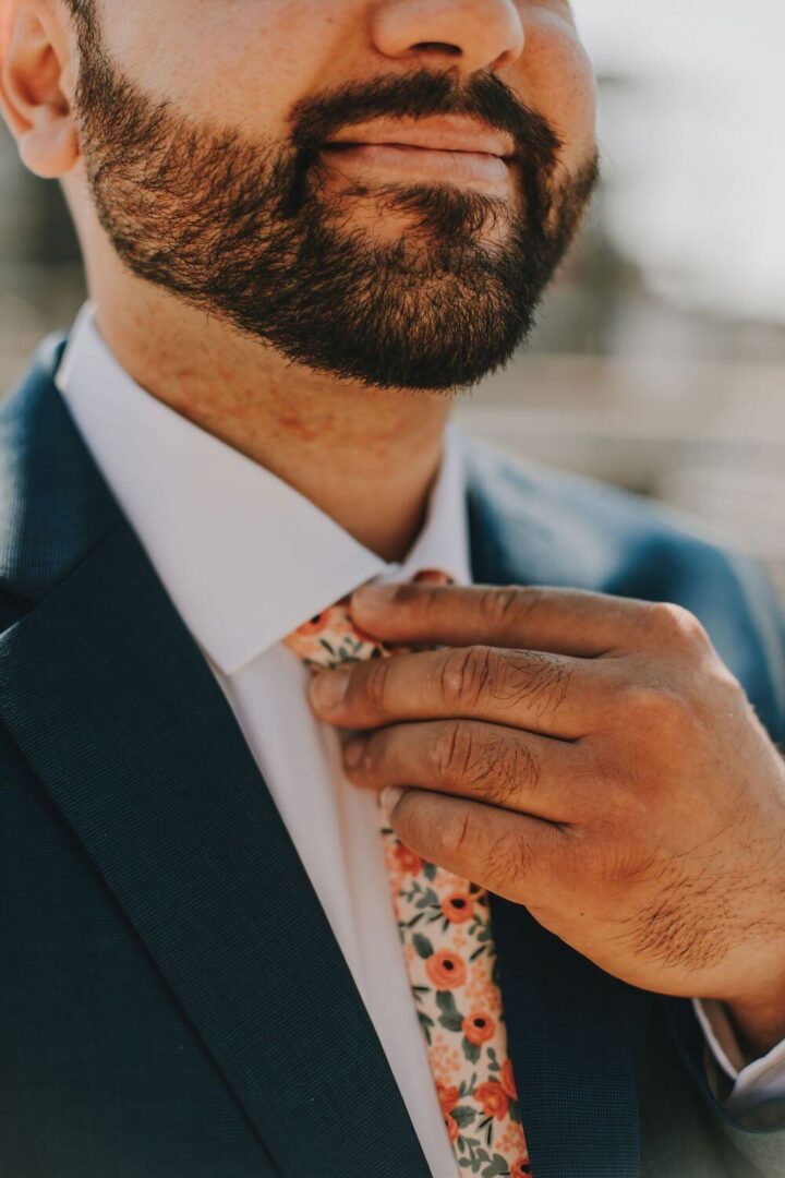 A man in a suit and tie adjusting his neck tie.