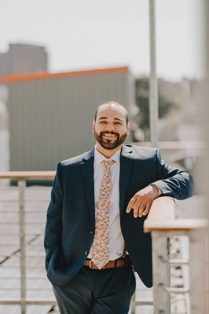 A man in suit and tie leaning on railing.