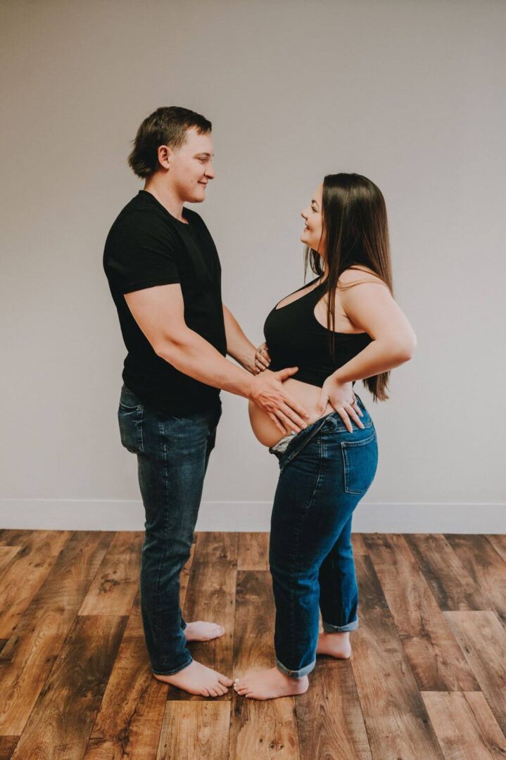 A man and woman holding hands in front of a wall.