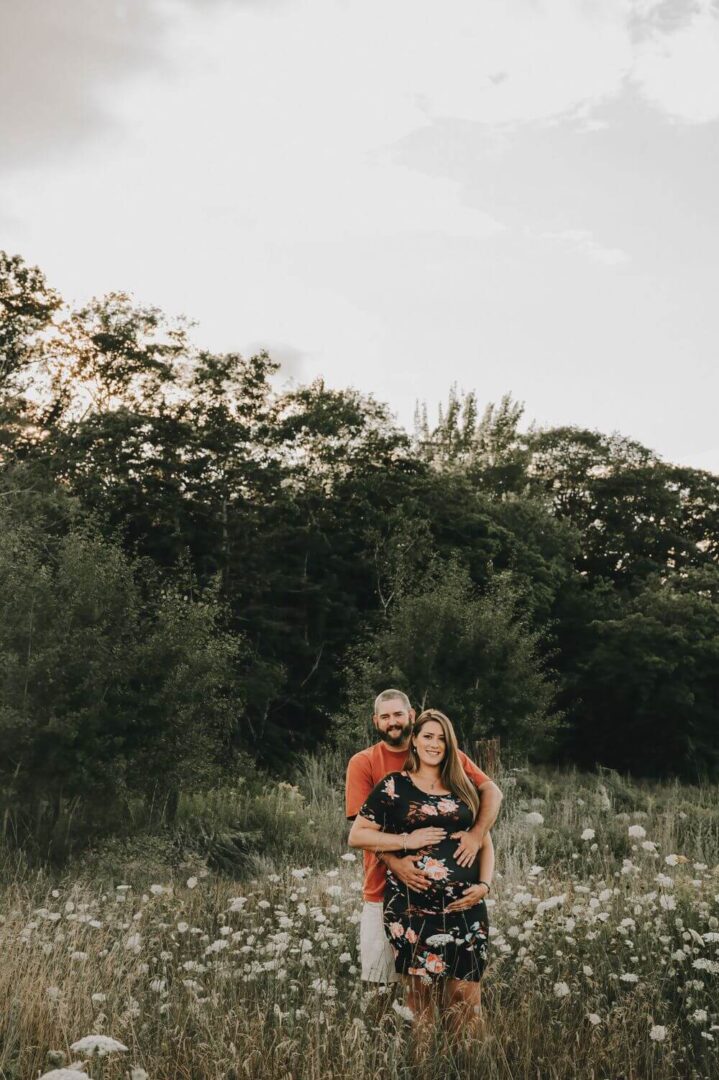 A man and woman posing for a picture in the woods.