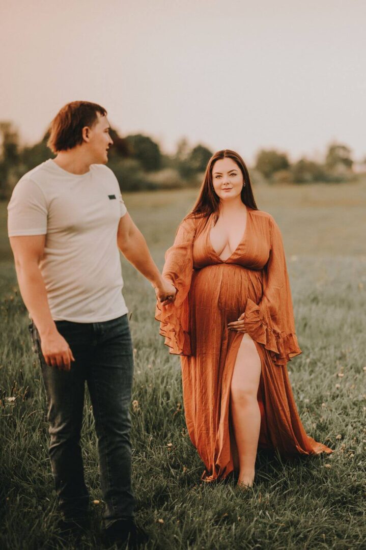 A man and woman holding hands in the grass.