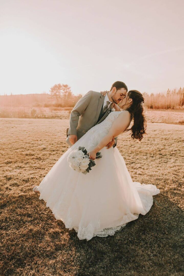 A man and woman kissing in the grass.