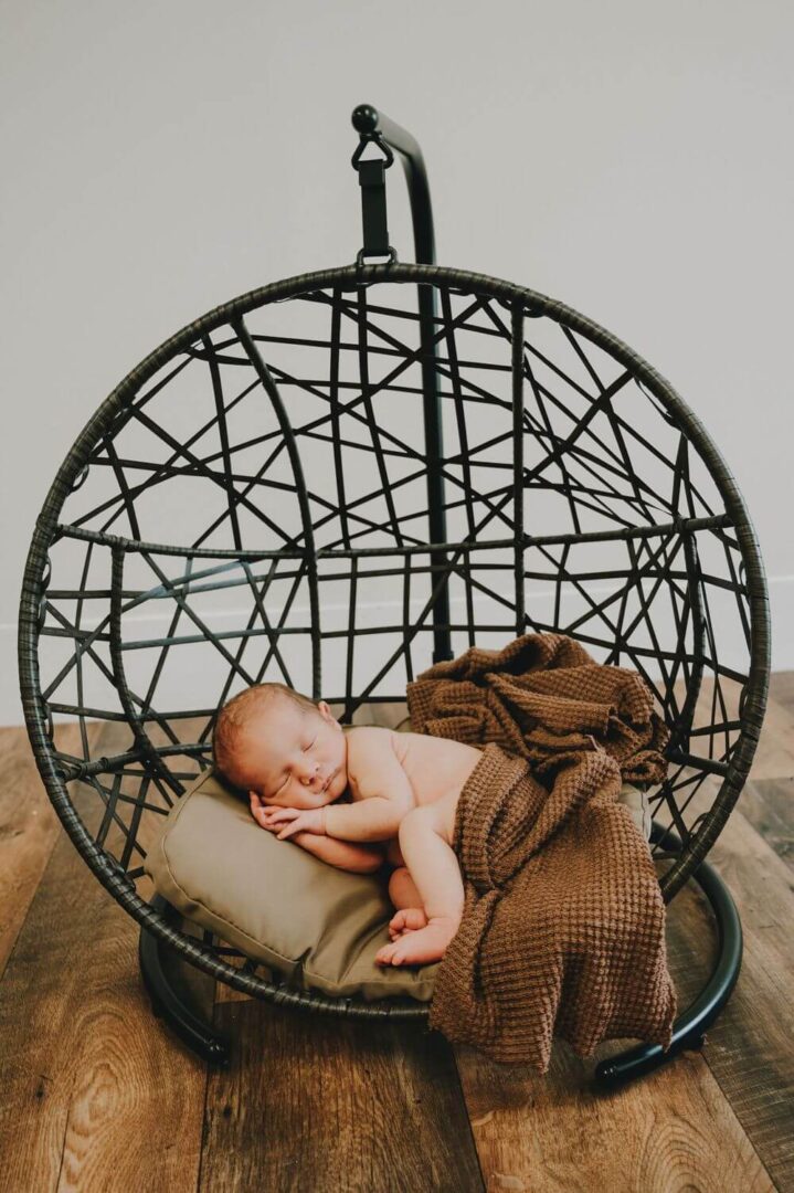 A baby is sleeping in a chair on top of a table.