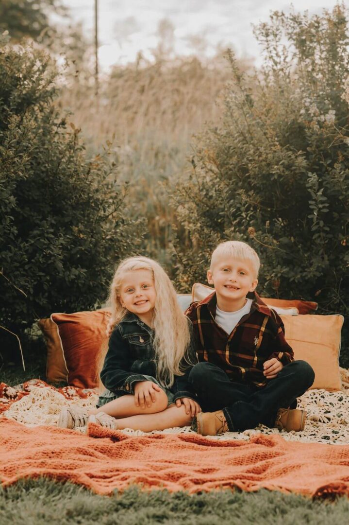 A young boy and girl sitting on the ground.