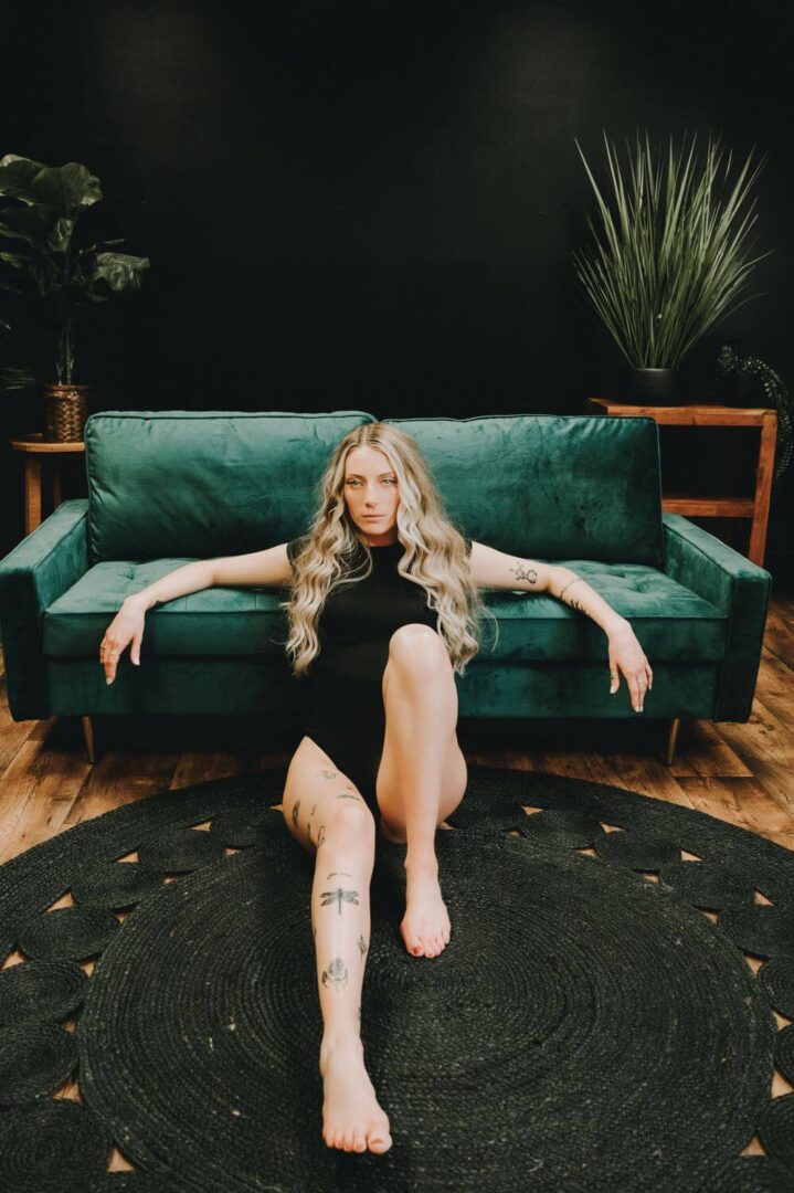 A woman sitting on the floor in front of a couch.