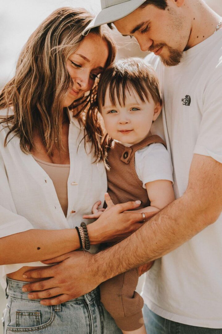 A woman holding a baby and standing next to another man.