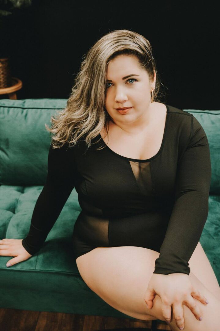 A woman sitting on top of a couch wearing black lingerie.