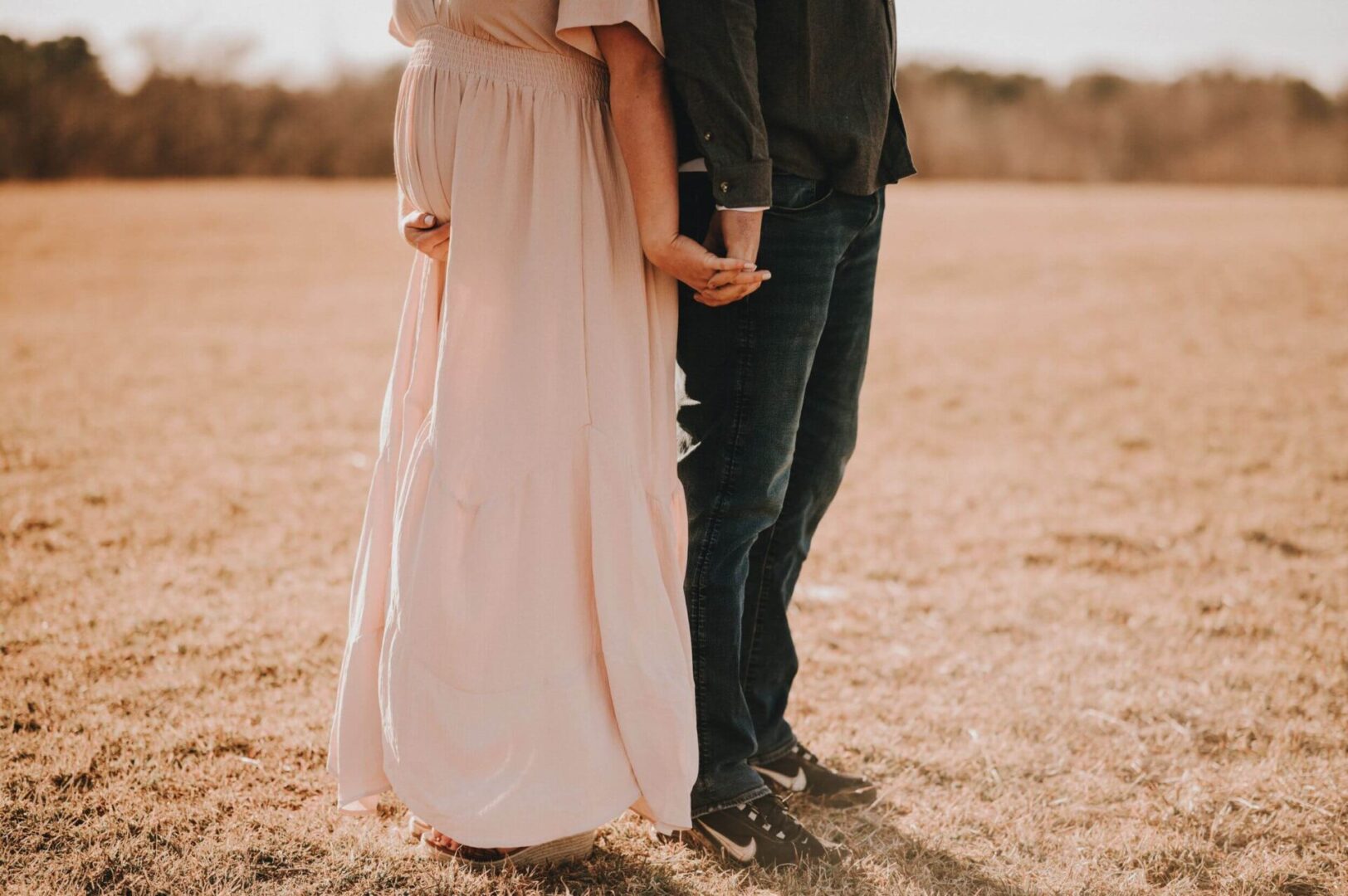 A man and woman holding hands in the middle of an open field.