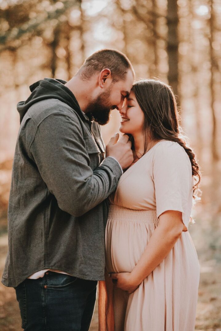 A man and woman kissing in the woods.