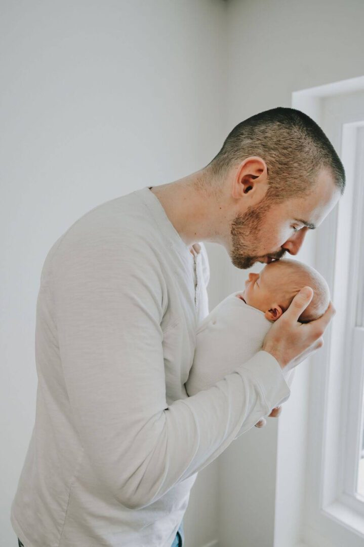 A man holding his baby in front of the mirror.