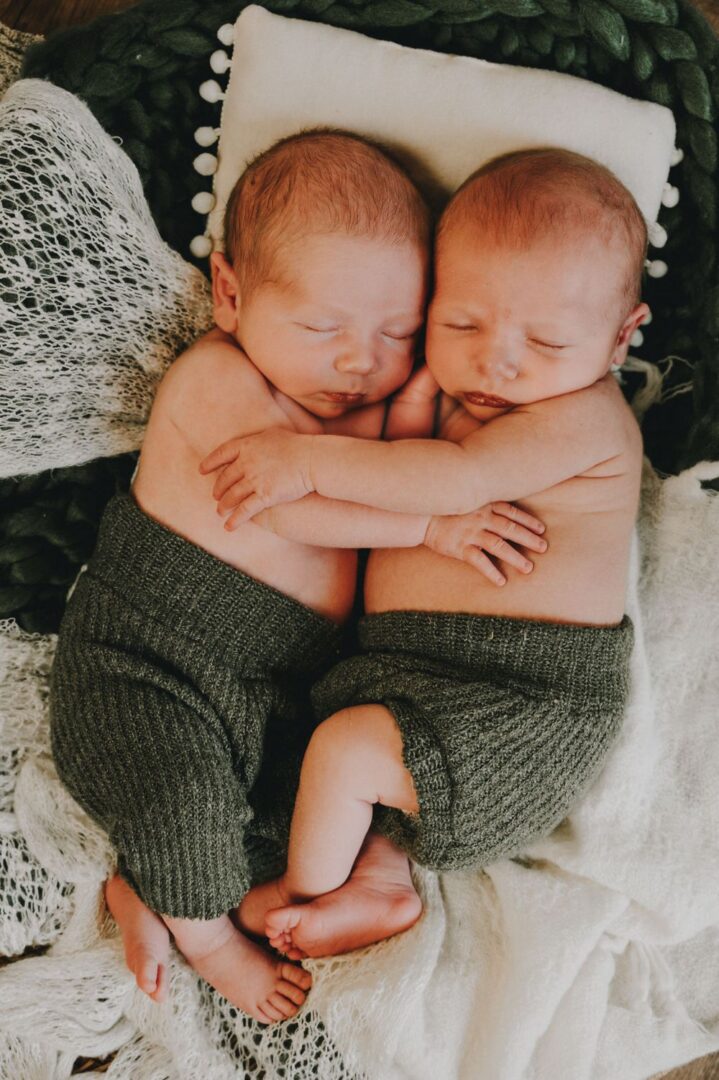 Two babies are sleeping on a blanket.