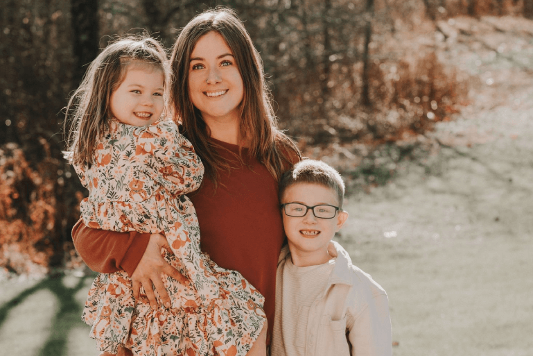 A woman holding two children and posing for the camera.